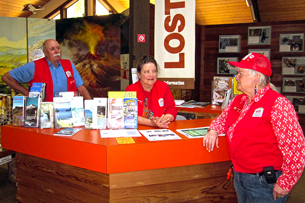 Three volunteers wait to greet visitors